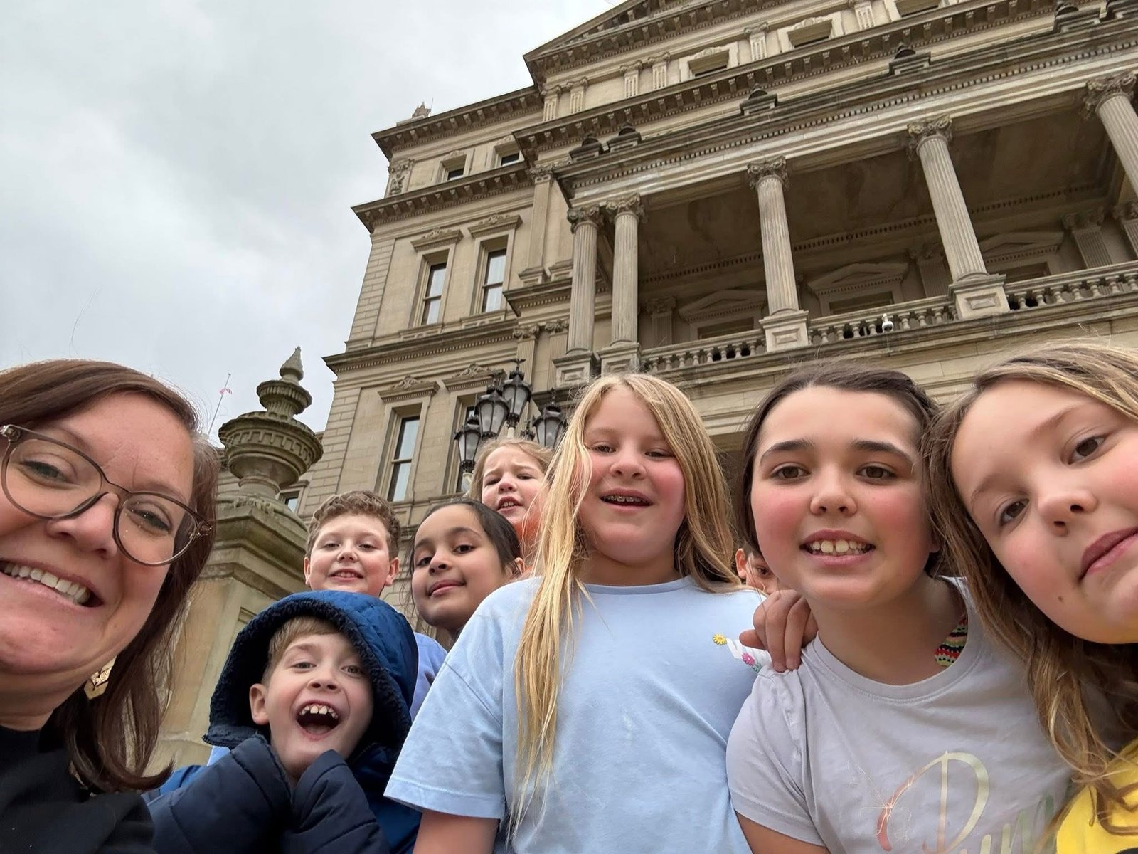 A Zion Lutheran teacher and her students smiling together on a field trip to the Michigan Capitol