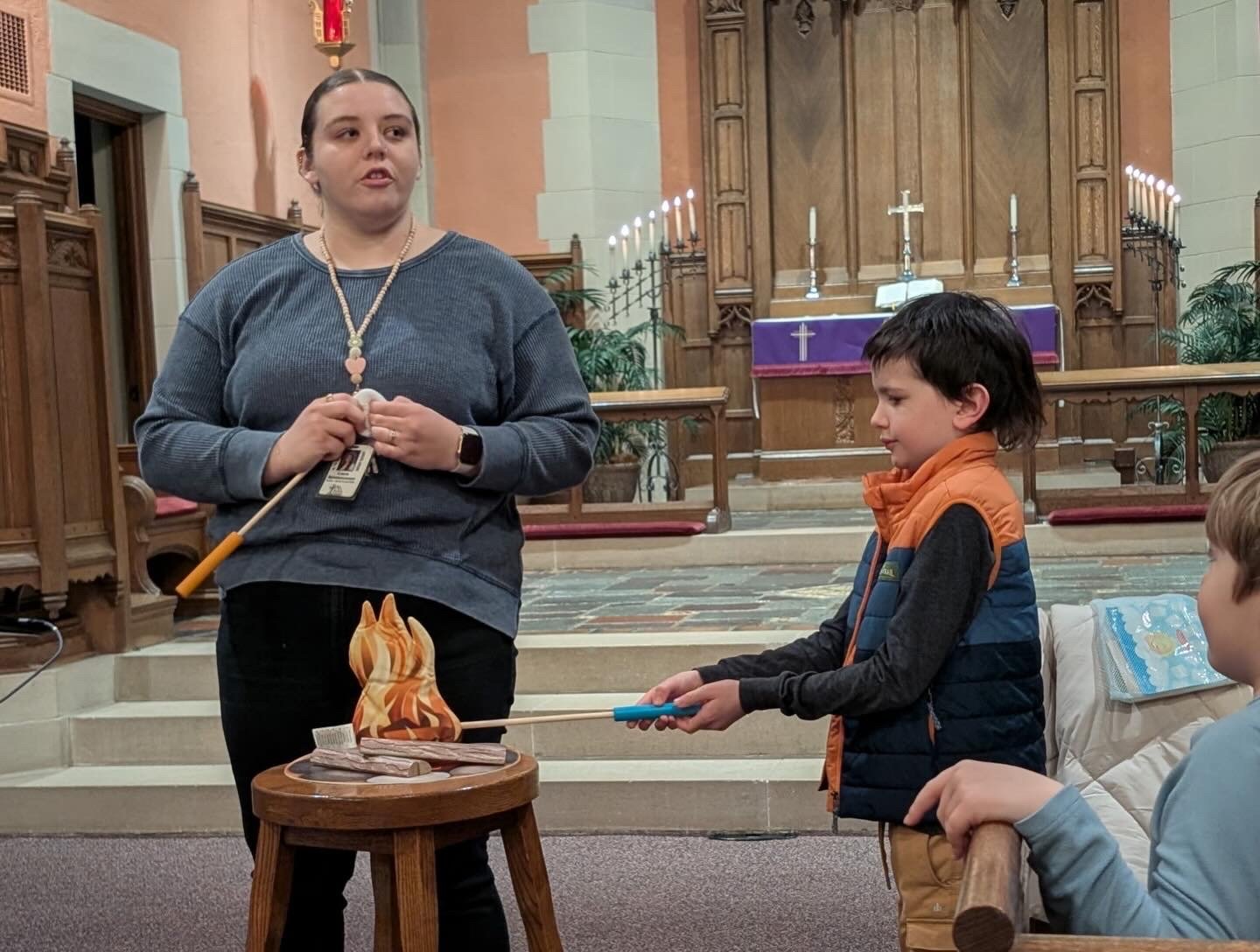 A Zion Lutheran teacher kneeling beside a student during a chapel object lesson
