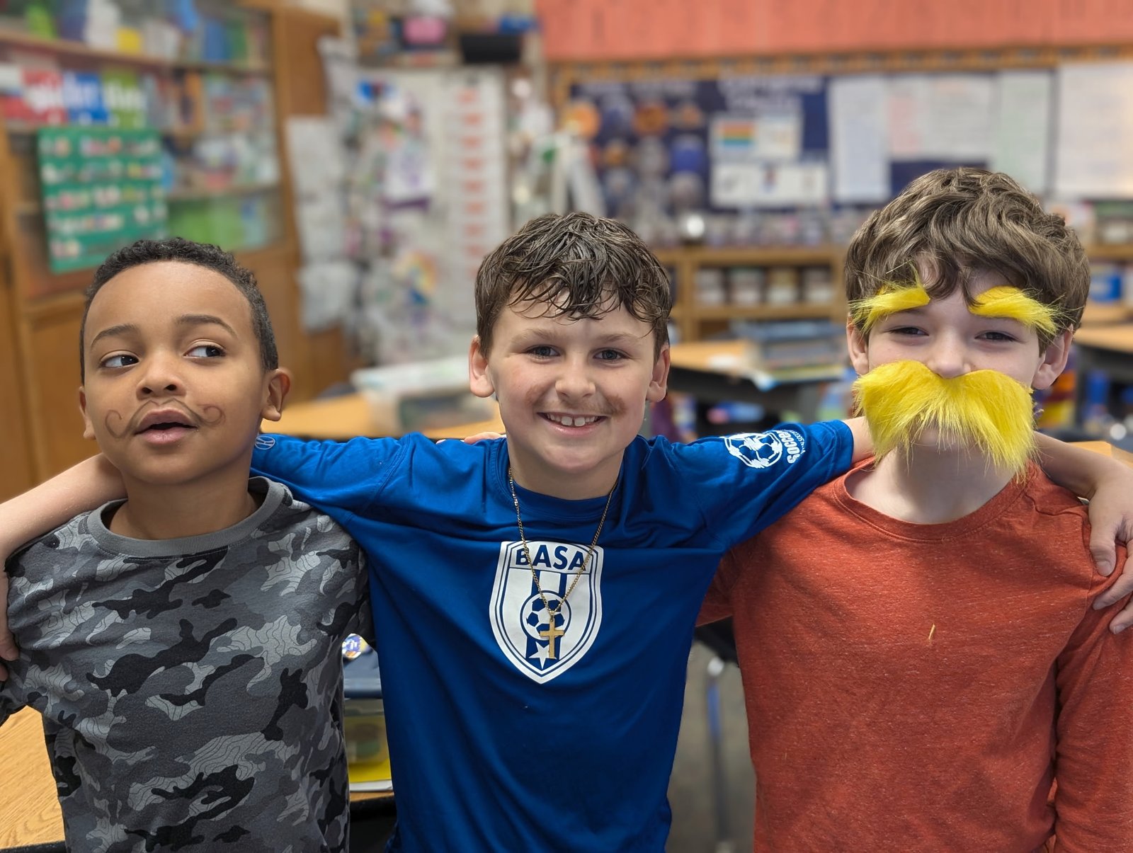 Three Zion Lutheran students smiling with arms around each other in their classroom
