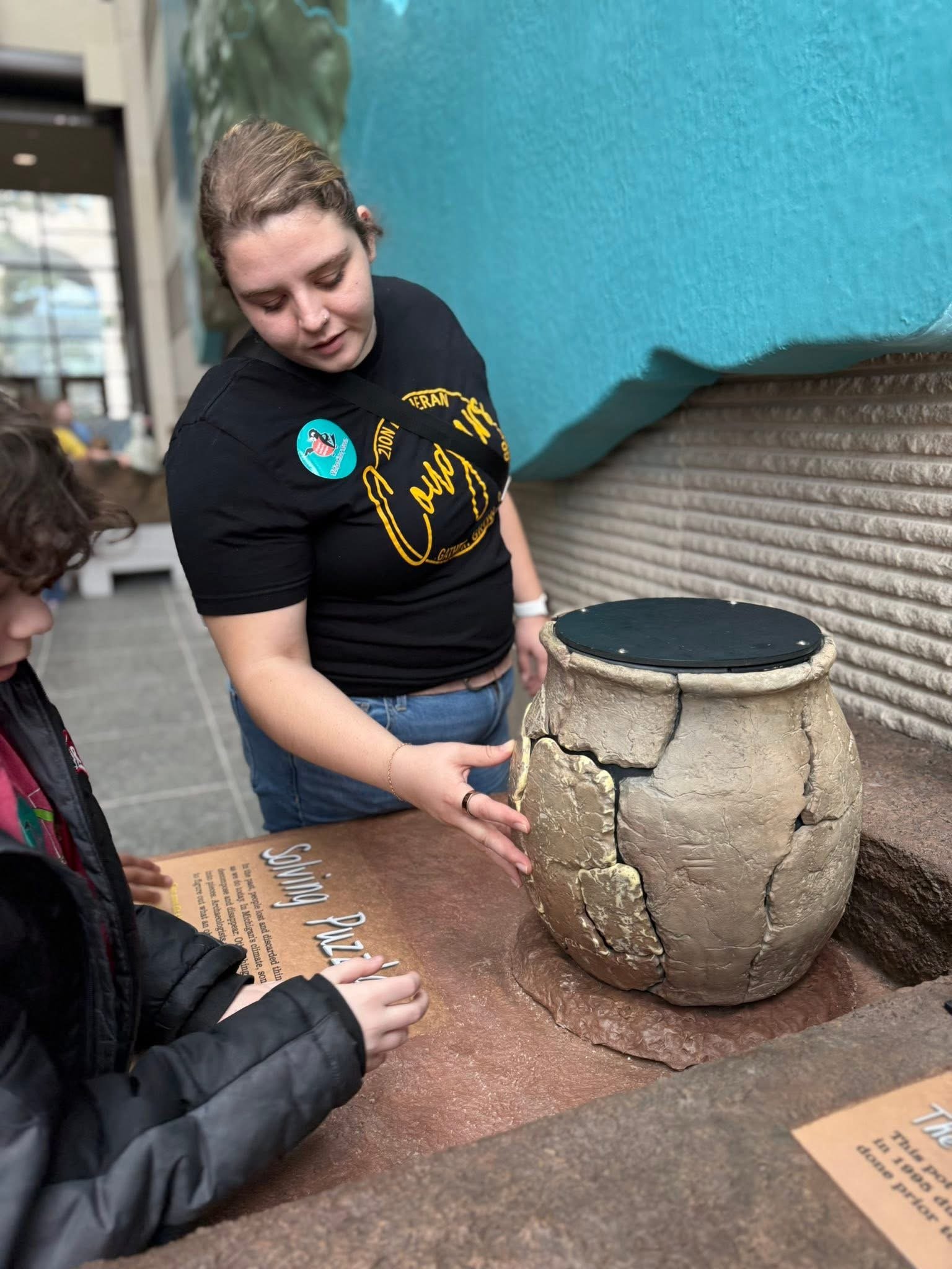 A Zion Lutheran teacher guiding a young student through a hands-on museum exhibit